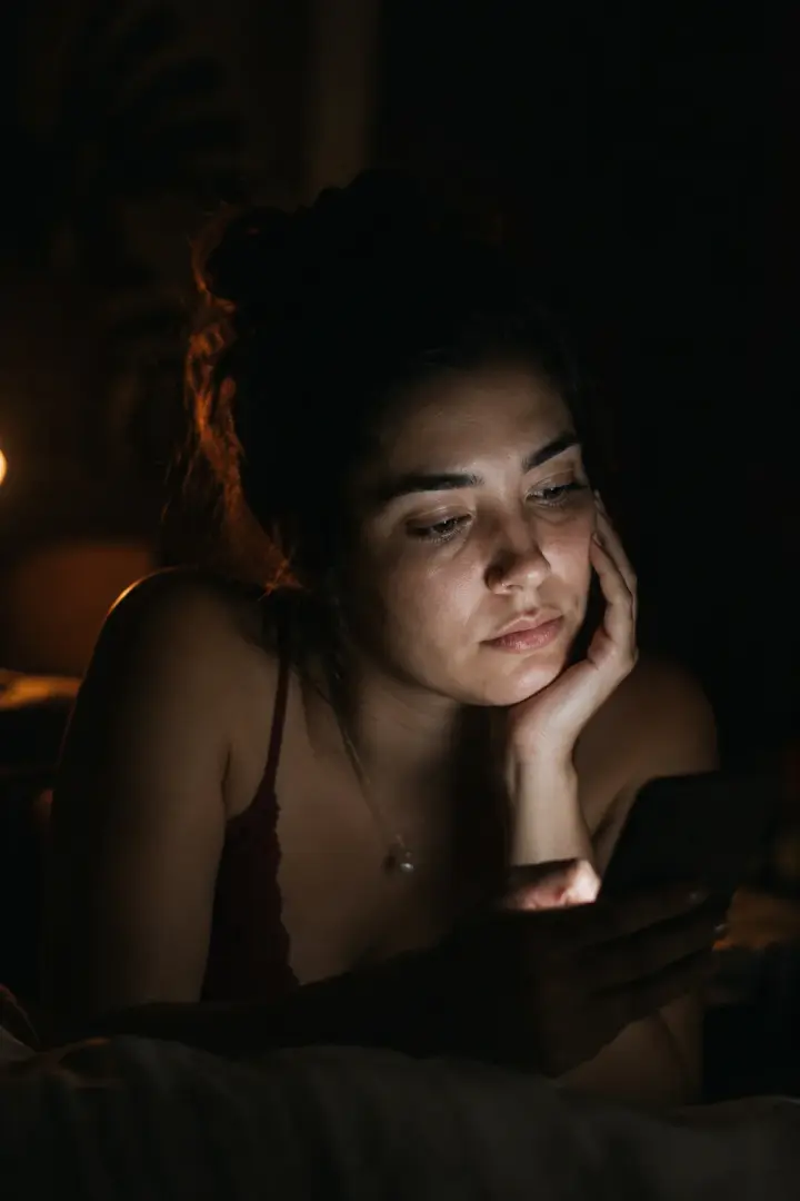 Mulher à noite, o rosto iluminado pela luz do celular